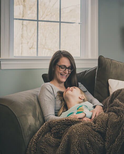 Family snuggled with blankets on couch in heated home