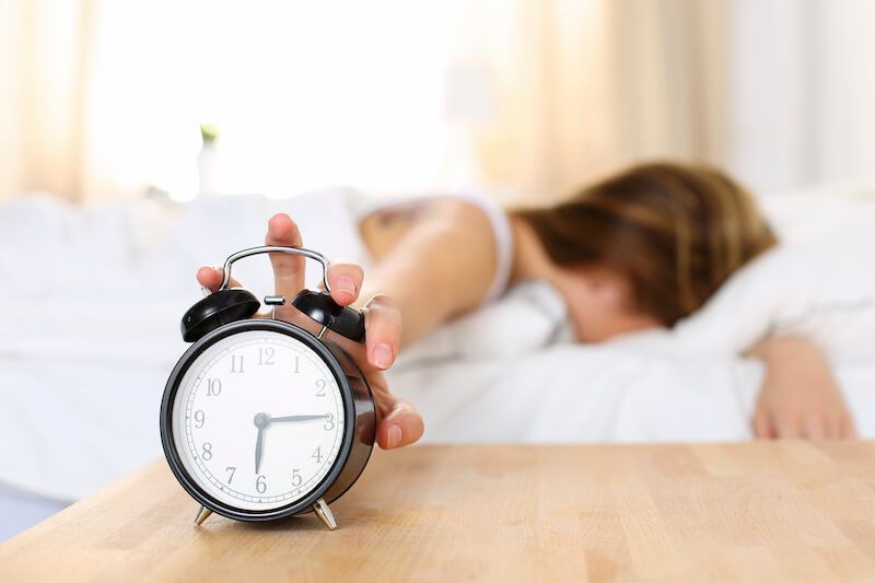 Woman turning alarm clock off early in the morning