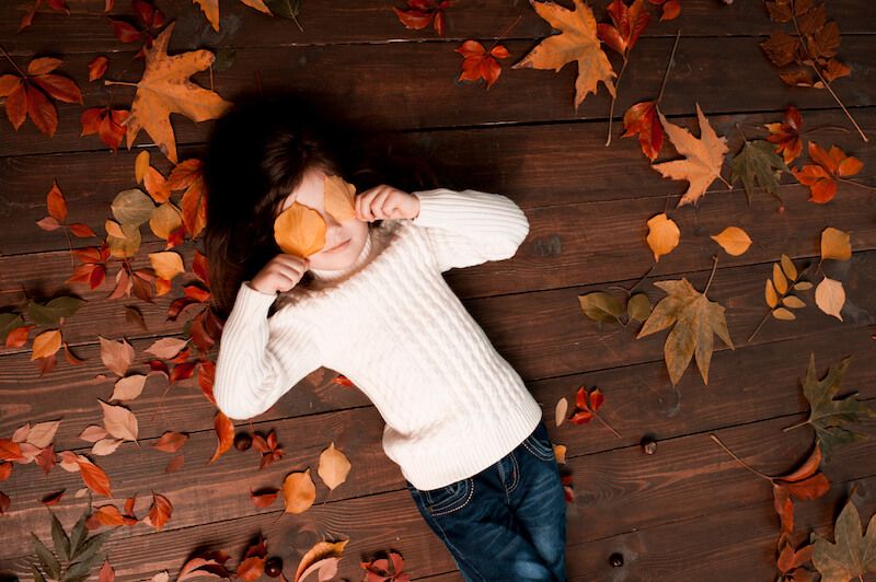 Young girl playing in leaves
